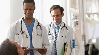 Two doctors in white lab coats speaking with a patient.