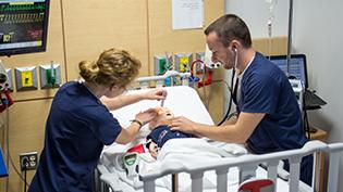 Male 和 female nursing students work in the simulation lab